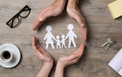 Rappresentazione di una famiglia circondata dalle mani di due persone, simboleggiando protezione e cura