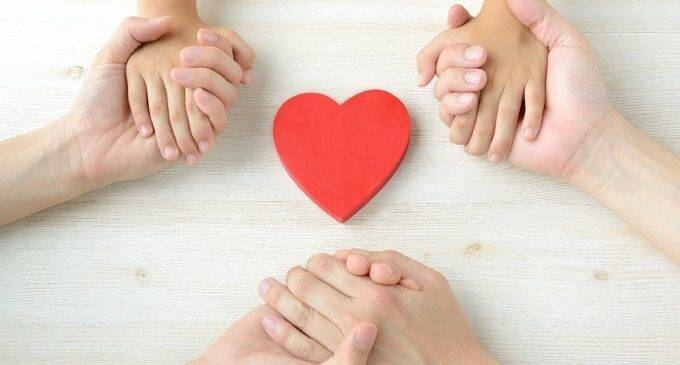 Cuore rosso al centro e intorno tre coppie di mani che si stringono