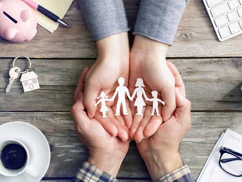 Una famiglia è rappresentata tra le mani di due persone, che la sostengono con cura e protezione