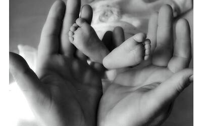 Foto in bianco e nero che mostra i piedini di un neonato tra le mani di un adulto, esprimendo amore e cura