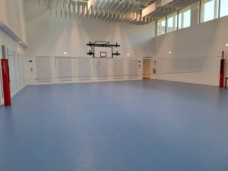 la palestra della scuola media con canestro da basket e rete da pallavolo